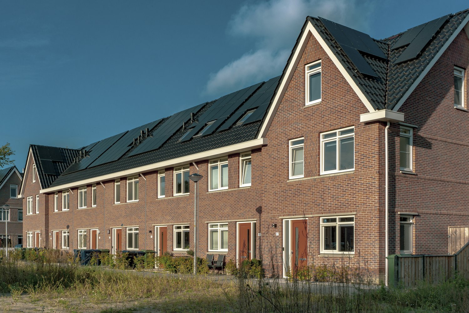 Nieuwbouw rijtjeshuizen van baksteen in Almere met zwarte zonnepanelen op het dak